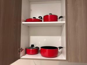 three red pots and pans sitting on shelves in a kitchen at HARF310 Modern Studio w Balcony at Yas Island in Abu Dhabi +12 photos