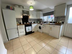 a kitchen with white cabinets and a washer and dryer at Mercer House in Lisburn
