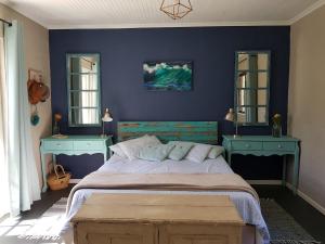 a bedroom with a bed with blue walls and mirrors at Glen Valley Cottage in Glencairn