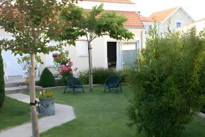 a garden with chairs and a tree and a house at Au Paradis Des Hotes - Chambre Ile in Fouras +2 photos
