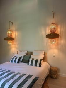 a bedroom with a bed with striped pillows and lights at Sainte Raphine in Fargues-Saint-Hilaire +12 photos