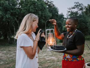 two women are holding a lantern in a field at Rhino's Rest Private Luxury Villa in Hoedspruit