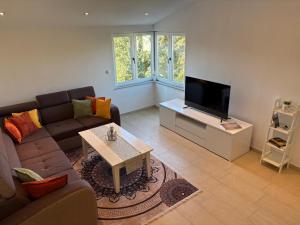 Una sala de estar con un sofá y un televisor de pantalla plana. en Kuća Gabriele, en Ljubuški