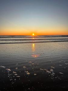 een zonsondergang op een strand met de oceaan bij Complejo Gerar in Las Toninas
