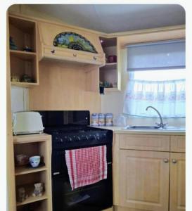 cocina con fogones negros y fregadero en Cosy 8 Berth Caravan At Southview Park In Skegness Ref 33024E, en Winthorpe 3 fotos más
