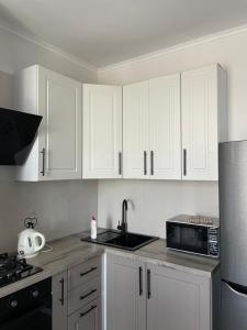 a kitchen with white cabinets and a sink and a microwave at Авторский in Fontanka