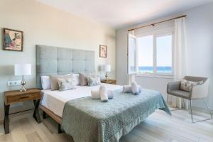 a bedroom with a bed and a chair and a window at Villa Marnes by Menorca Vacations in Son Bou +21 photos