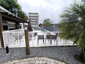 una recinzione bianca con sedie e un ombrellone accanto a una piscina di Apartamento 2 quartos Blumenau a 10 minutos da Vila Germânica a Blumenau