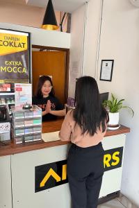 a woman standing at a counter in front of a customer at Anders Arjuna Selatan in Jakarta +14 photos