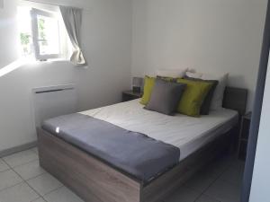 Un dormitorio con una cama con almohadas verdes y una ventana. en Charmant logement lumineux - Terrasse privee - Wifi, en La Chaussée-Saint-Victor