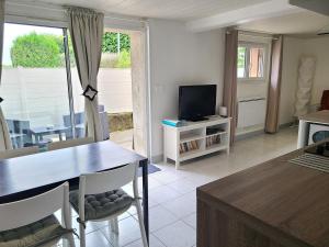 Una sala de estar con una mesa y un televisor. en Charmant logement lumineux - Terrasse privee - Wifi, en La Chaussée-Saint-Victor