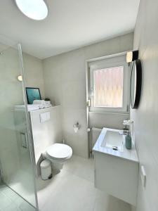 a white bathroom with a toilet and a sink at Basilisk Homes - in Grenzach-Wyhlen bei Basel - 4 x Moderne Fewos je 1bis2, 1bis4 oder 1bis6 Pers mit Küche und Balkon oder Terrasse - Parkplätze vorhanden in Grenzach-Wyhlen