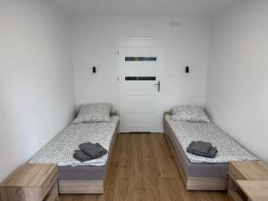 two beds in a room with white walls and wooden floors at Herman Pokoje - nr 8 in Hermanowice