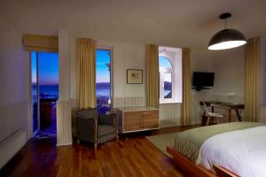 a bedroom with a bed and a desk and windows at Palacio Astoreca in Valparaíso