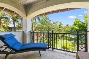 Un patio con una silla azul en un balcón. en Fairways Mauna Lani 1406 condo, en Waikoloa