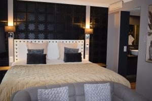 a bedroom with a large bed and a couch at Le Trophée Boutique Hôtel Spa- La Loggia Appart'hôtel in Deauville