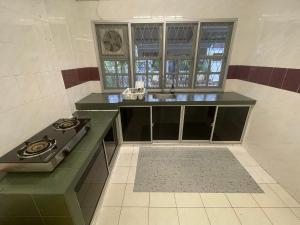 a kitchen with a sink and a stove in it at Authentic Local Terrace House in Kuching in Kuching