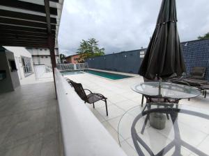 patio con tavolo, ombrellone e piscina di Apartamento 2 quartos Blumenau a 10 minutos da Vila Germânica a Blumenau