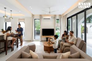 a family sitting in a living room with a tv at StayVista at Roźe Home with Open Terrace, Pool & Pet Friendly in Calangute