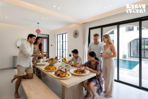 a group of people standing around a table with food at StayVista at Roźe Home with Open Terrace, Pool & Pet Friendly in Calangute