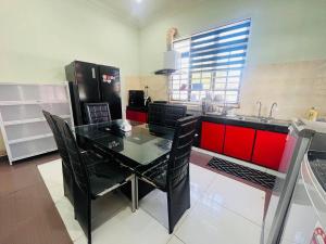 a kitchen with a black table and red cabinets at Villa Axalea Kuala Terengganu in Kuala Terengganu