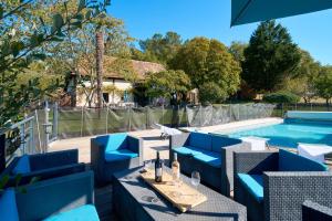 a patio with blue chairs and a swimming pool at Gite La Périgourdine in Saint-Laurent-des-Hommes