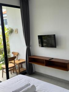 a bedroom with a desk and a tv on a wall at Famiglie Guest House in Canggu
