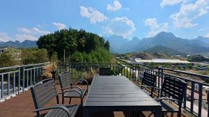 a wooden table and chairs on a balcony with mountains at Yesuhanshe Homestay in Zhangjiajie