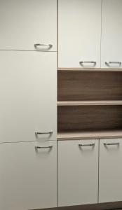 una cocina blanca con armarios blancos y detalles en madera en Apartment - Dürer Blick, en Mühlhausen