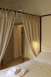 a bedroom with a bed with white sheets and curtains at Casa Zarinelli in Castagneto Carducci