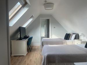 a bedroom with two beds and a desk with a television at Madonna Halley Hotel in Edgware +2 photos