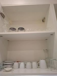a white shelf with cups and bowls on it at My Room Luzern in Luzern +8 photos