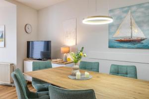 a dining room with a wooden table and green chairs at Sünnslag 103 - "Ferienhaus Ostseezauber" - 4 Zimmer, im Herzen Boltenhagens in Boltenhagen
