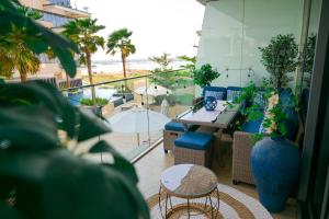 阿布扎比Beachside Sunset Residence的配有桌椅的阳台，可欣赏海滩美景