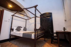 a bedroom with a canopy bed and a table at Villa 1908 Hikkaduwa in Dodanduwa