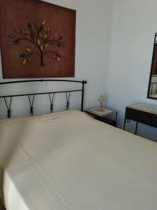 a bedroom with a bed with a painting on the wall at Vromolithos apartments in Nisís Léros +1 photo