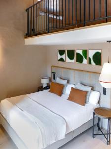 ムンカーダにあるTradere Hotel Boutiqueのオレンジ色の枕が付いた大きな白いベッドのある寝室