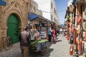 a group of people walking down a street in a market at Riad Lailouza in Essaouira