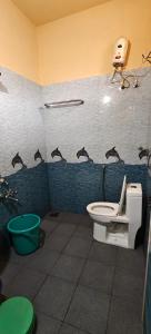 a bathroom with a toilet and a hair dryer on the wall at Sheshu Homestay in Māvalli