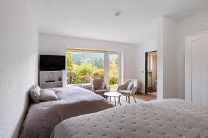 a white bedroom with two beds and a window at Ferienwohnung Wald-Ausblick in Willingen