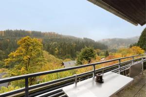 a white table on a balcony with a view of a forest at Ferienwohnung Wald-Ausblick in Willingen