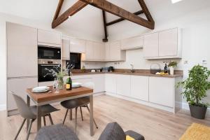 a kitchen with white cabinets and a wooden table at The Smithy at West Lyham in Chatton