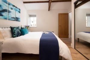 a bedroom with a large white bed with blue accents at The Smithy at West Lyham in Chatton