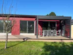 a red building with a deck with a table and chairs at Cottage Cafecouet'Breizh in Guipry-Messac