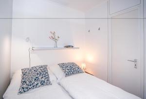 a white bed with two pillows and a shelf on the wall at Seerobbe in Hansaland