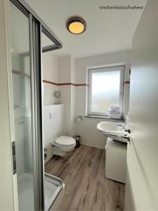 a white bathroom with a toilet and a sink at NB 15 - Ferienwohnung 2 Zimmer Seeblick Grimmershörn in Cuxhaven