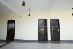 four elevators are lined up against a white wall at Keerthana Marriage hall and Rooms in Coimbatore