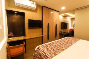 a hotel room with a bed and a flat screen tv at AR Suites Sohna Road in Gurgaon