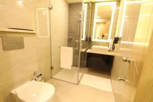 a bathroom with a shower and a toilet and a sink at AR Suites Sohna Road in Gurgaon +4 photos