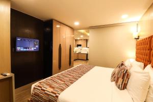 a hotel room with a bed and a flat screen tv at AR Suites Sohna Road in Gurgaon